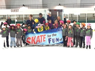 Large group of ice skating students and instructors with banner