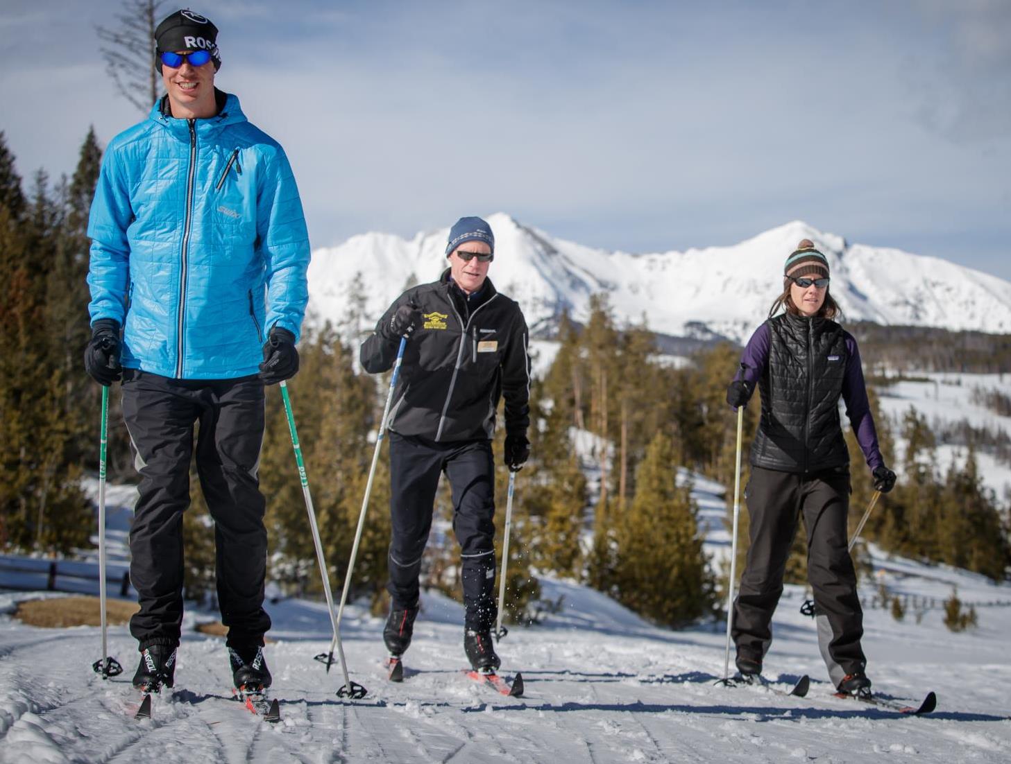 Two men and one woman Nordic skiing on a sunny day