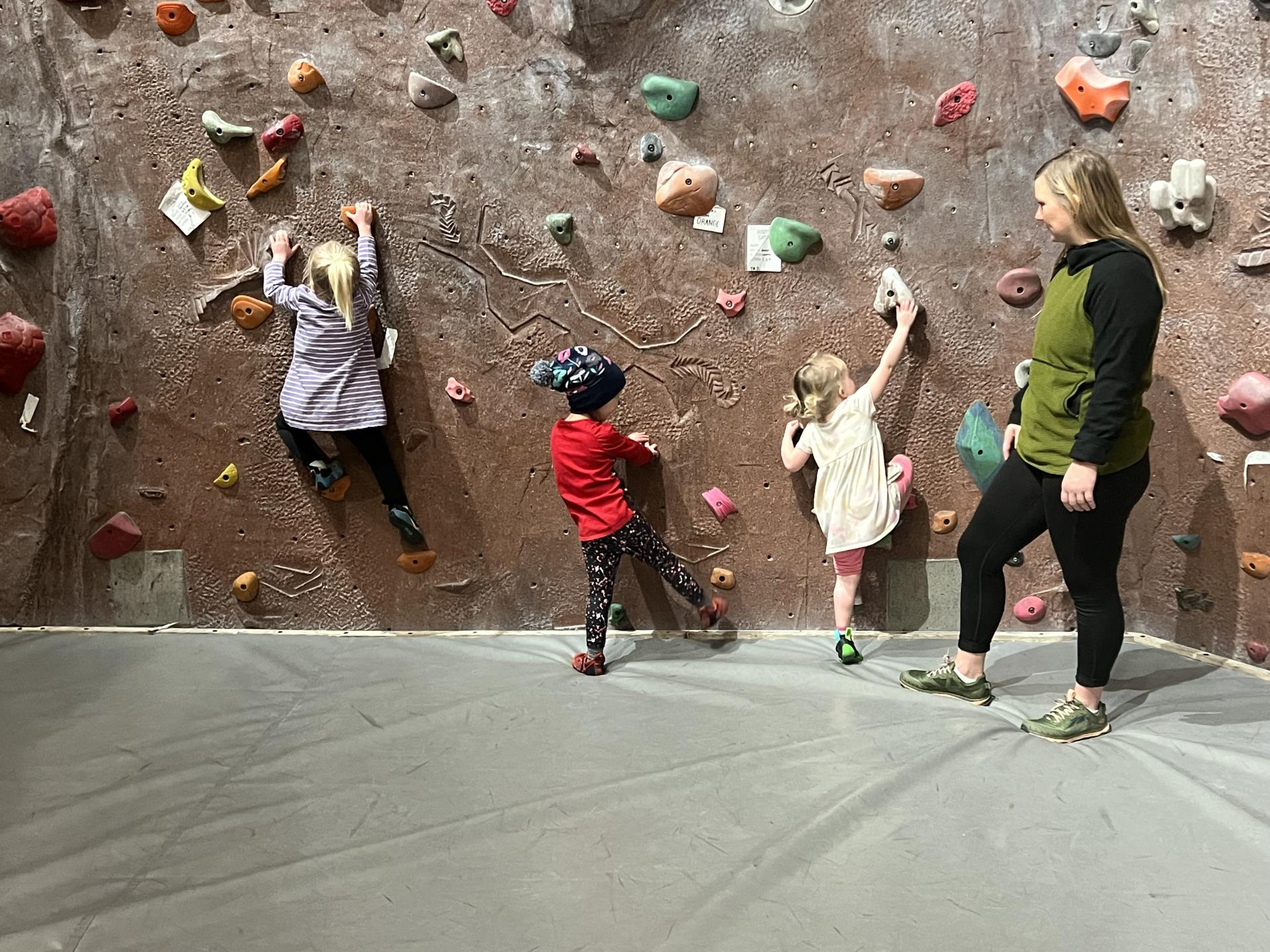 Three preschoolers on climbing wall with instructor