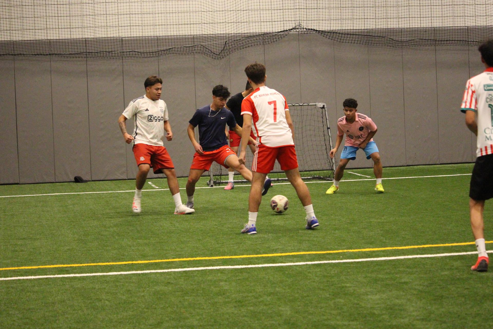 Six males playing indoor turf soccer